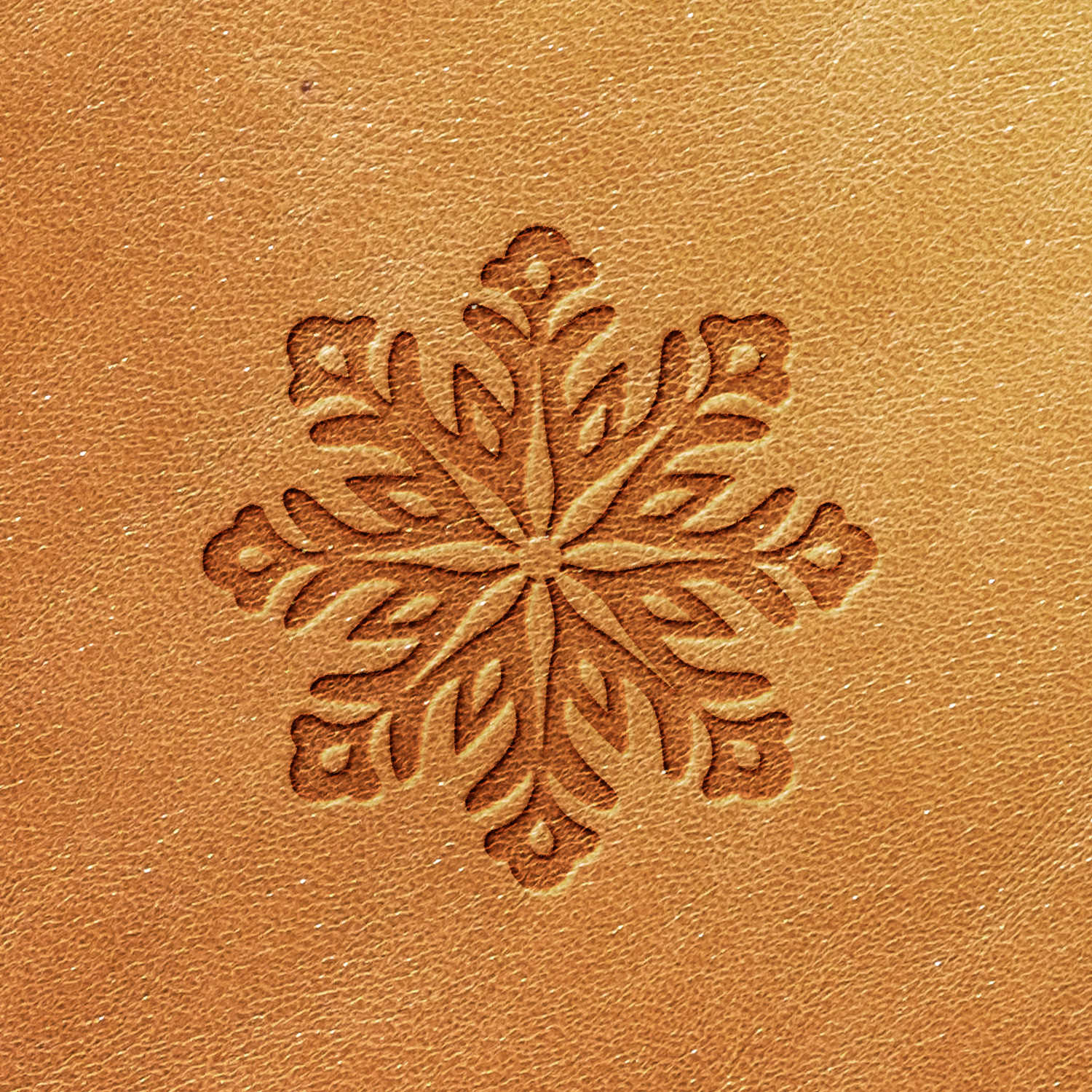 The Snowflake Delrin Leather Stamp creates a stunning symmetrical snowflake pattern on a light brown leather surface. The detailed design features intricate, swirling branches that add texture and stand out beautifully against the smooth background, lending an elegant touch.