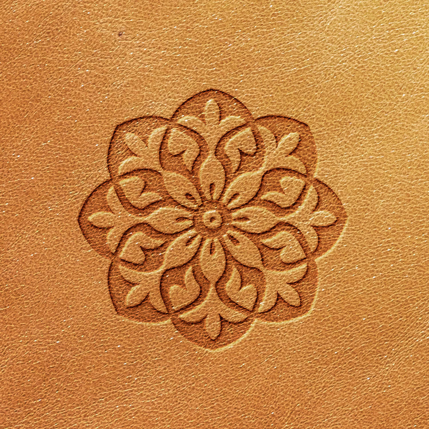 The Snowflake Delrin Leather Stamp creates a symmetrical floral pattern on a light brown leather surface. The design showcases intricate, stylized leaves and petals arranged in a circular shape. The uniformly colored textured leather accentuates the detailed artistry of this pattern.