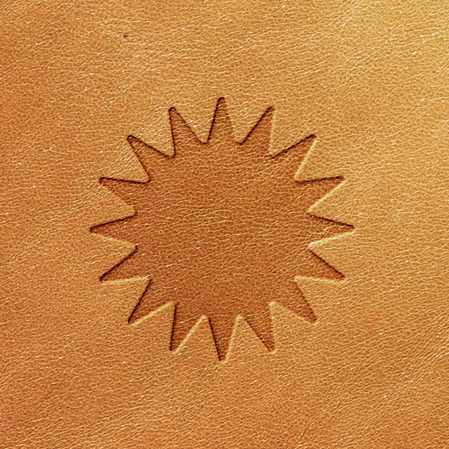 A close-up image showcasing the intricate, textured brown leather surface stamped with the Sunburst Delrin Leather Stamp, featuring an embossed sunburst design in the center with pointed rays radiating outward.