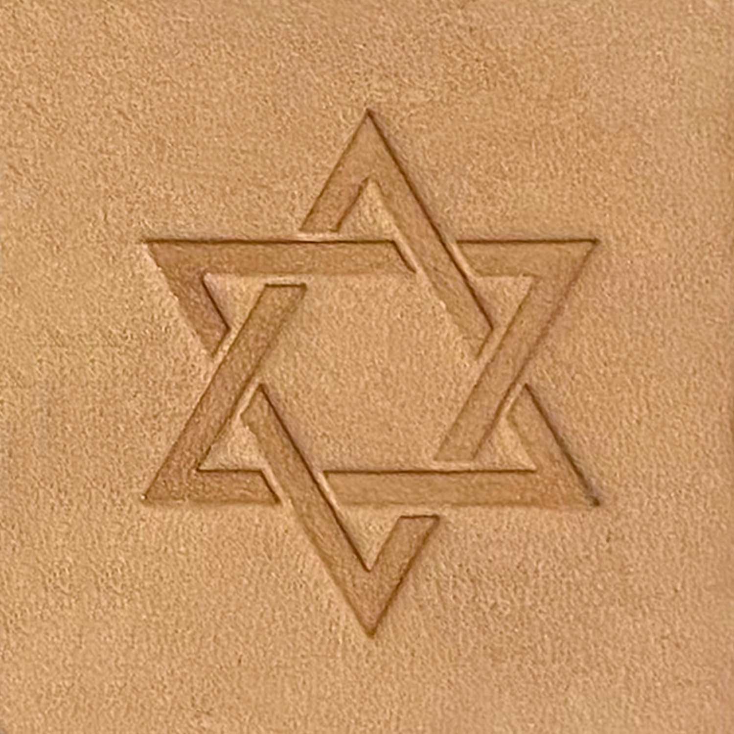 Product: The Star of David Delrin Leather Stamp features an embossed Star of David design on a beige textured surface. The intertwined triangles form a precise six-pointed star, giving it a geometric and symmetrical look. The background boasts a rough, sandpaper-like texture for added depth.