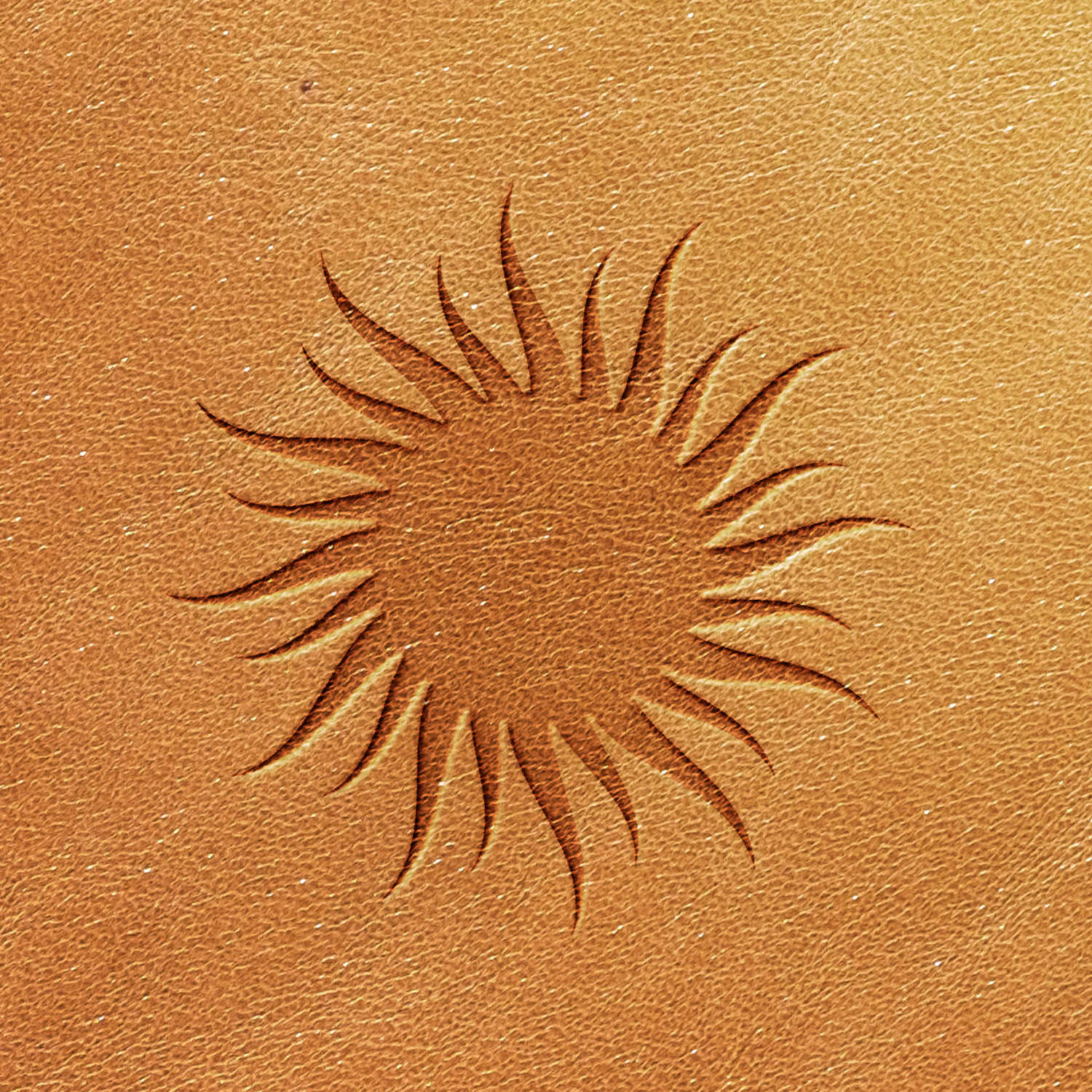 A close-up image of a sun design etched into a textured, tan-colored surface using the Sun Delrin Leather Stamp. The sun features a circular center with pointed rays extending outward in a wavy pattern.