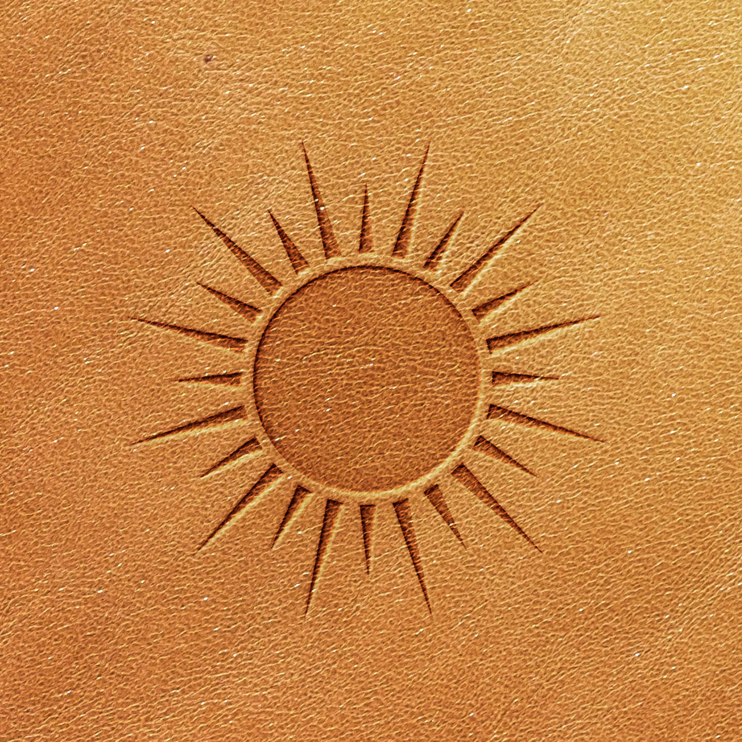 Up-close view of a circular sun design, created with the Sun Delrin Leather Stamp, embossed on a tan leather surface. The sun features rays radiating outward, giving it a detailed and textured appearance.