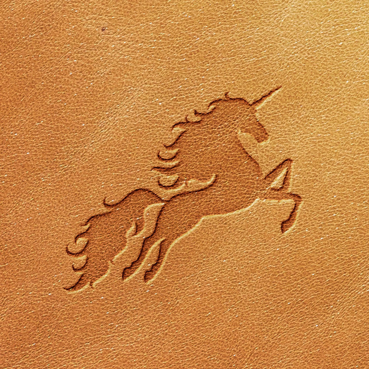 The Unicorn Delrin Leather Stamp creates an embossed image of a unicorn rearing with its mane and tail flowing on a tan-colored leather surface. The visible texture of the leather adds depth to the detailed embossed design.