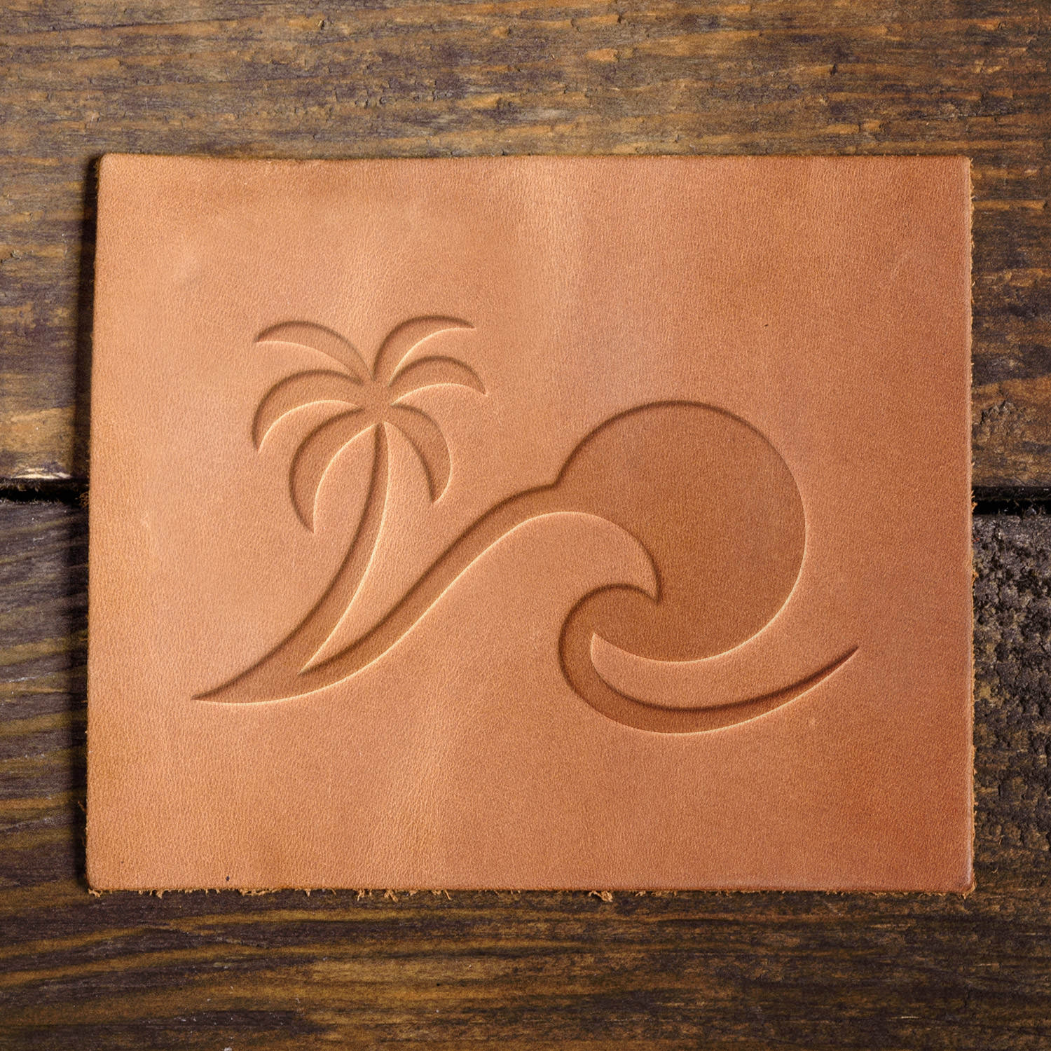 Leather sample featuring an embossed tropical wave and palm tree, ideal for ocean-inspired designs.