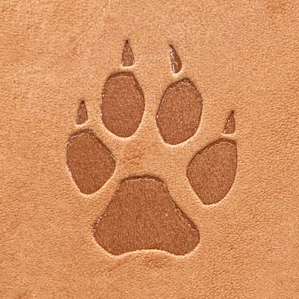 Natural veg-tan leather stamped with a clawed animal paw print using a Delrin leather stamp, showing defined toe pads and claw details.