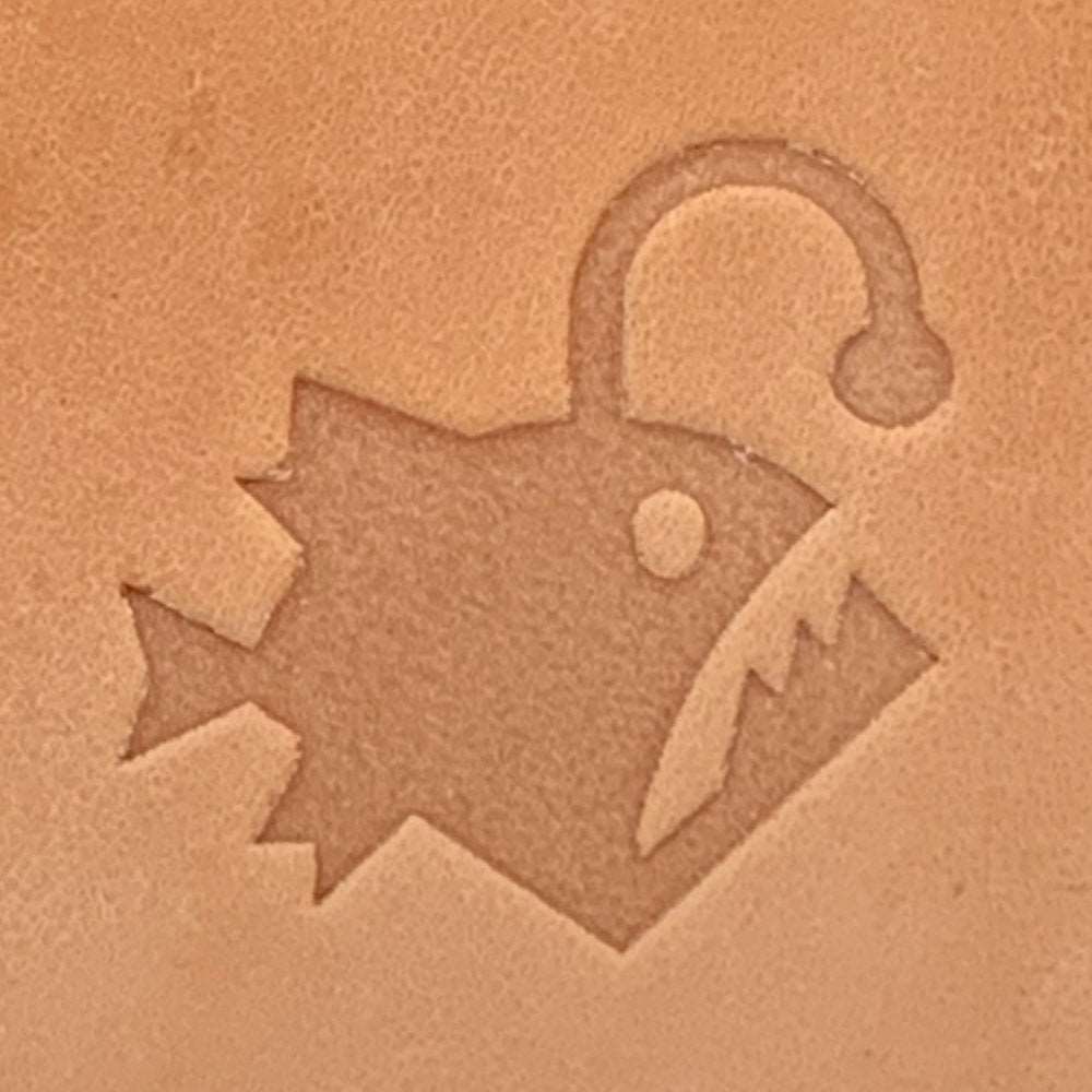 Stamped impression of an angler fish with a raised lure, made using a Delrin leather stamp on natural veg-tan leather.