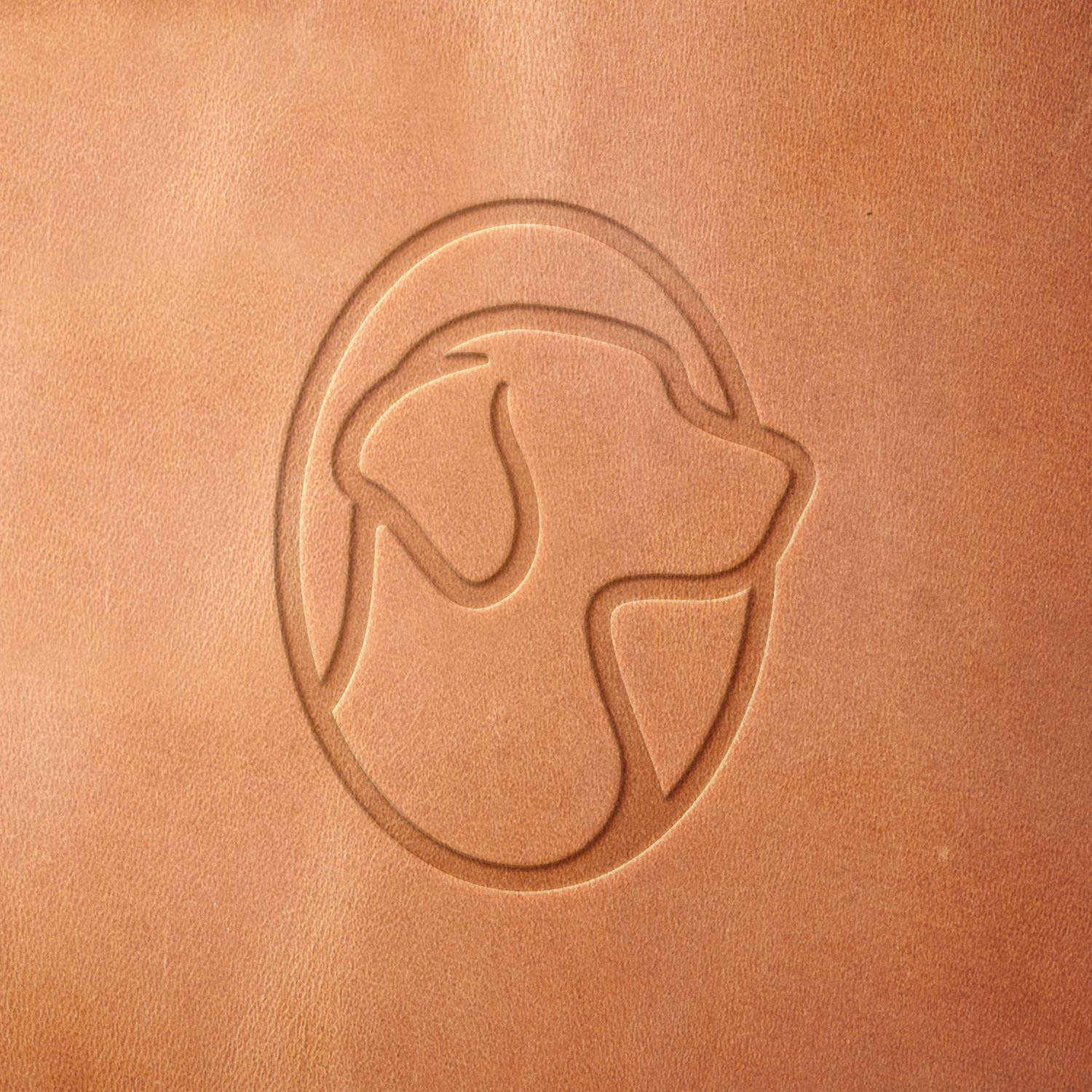 Leather sample with a stamped dog silhouette in an oval frame, created using a Delrin leather stamp—ideal for custom pet accessories, leather patches, and canine-themed designs.