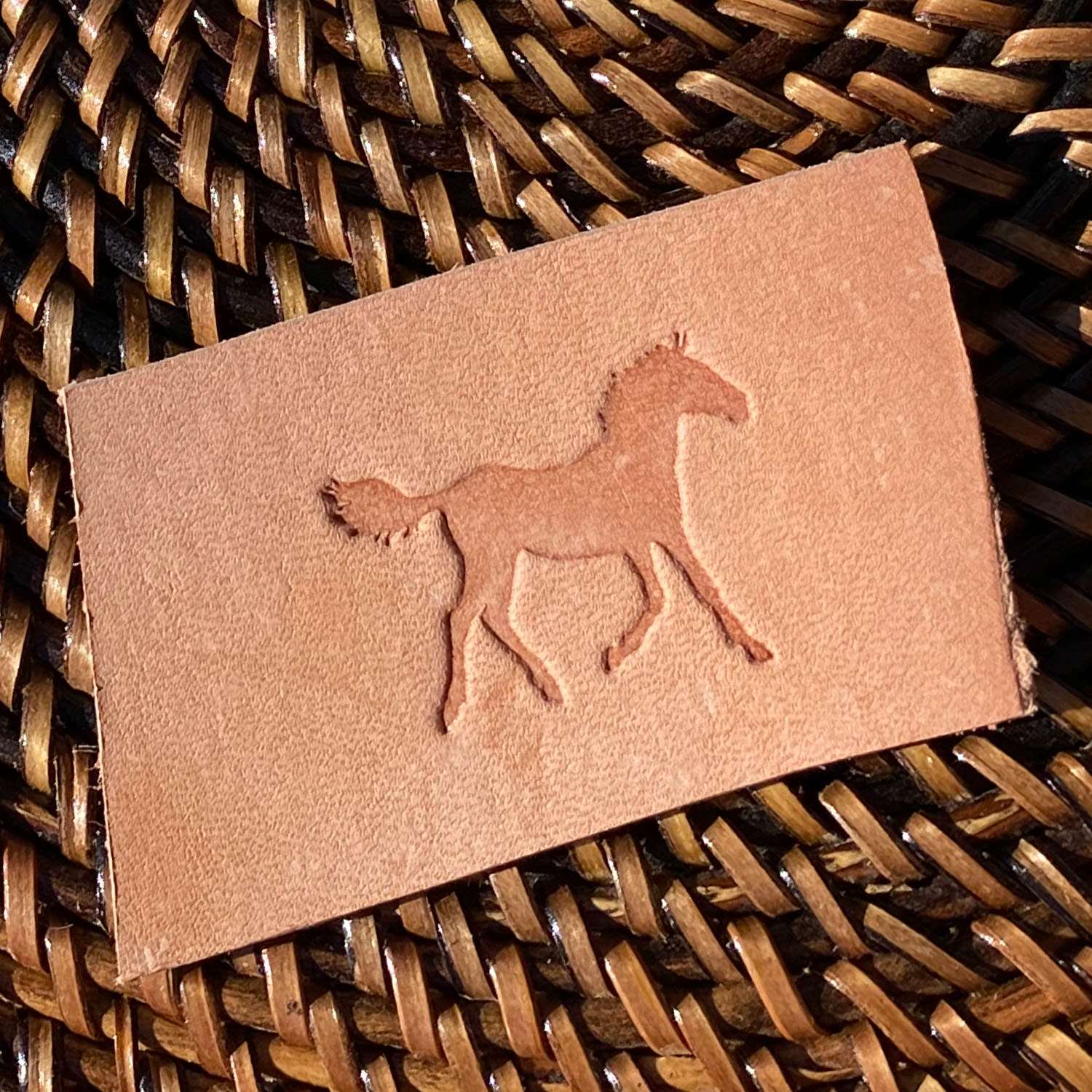 Stamped impression of a walking horse made with a Delrin leather stamp on natural veg-tan leather.