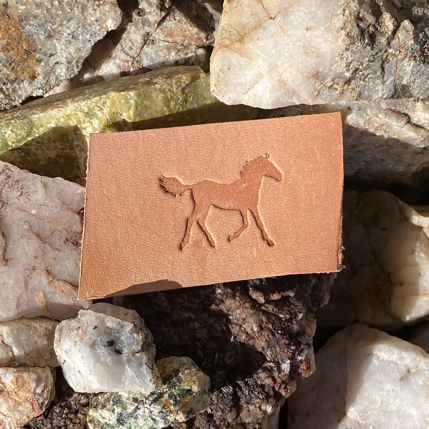 Stamped impression of a walking horse made with a Delrin leather stamp on natural veg-tan leather.