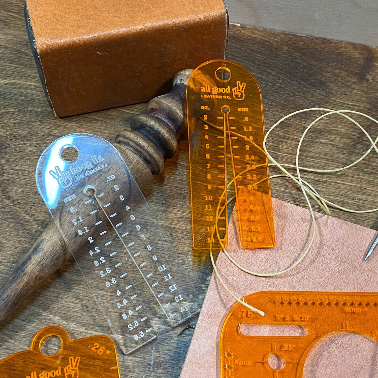 Leather thickness gauge tool used on a workbench alongside leatherworking tools and materials