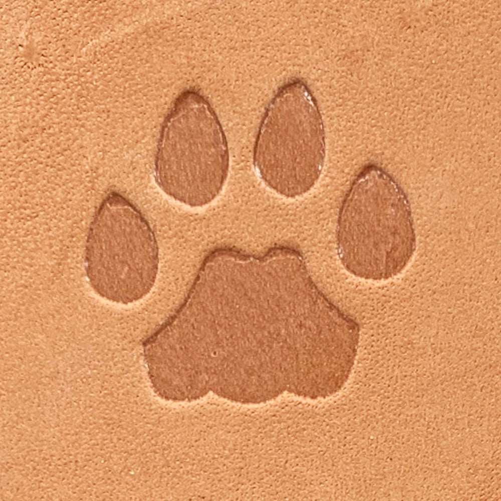 Natural veg-tan leather stamped with a paw print silhouette using a Delrin leather stamp, showing smooth edges and bold shape.