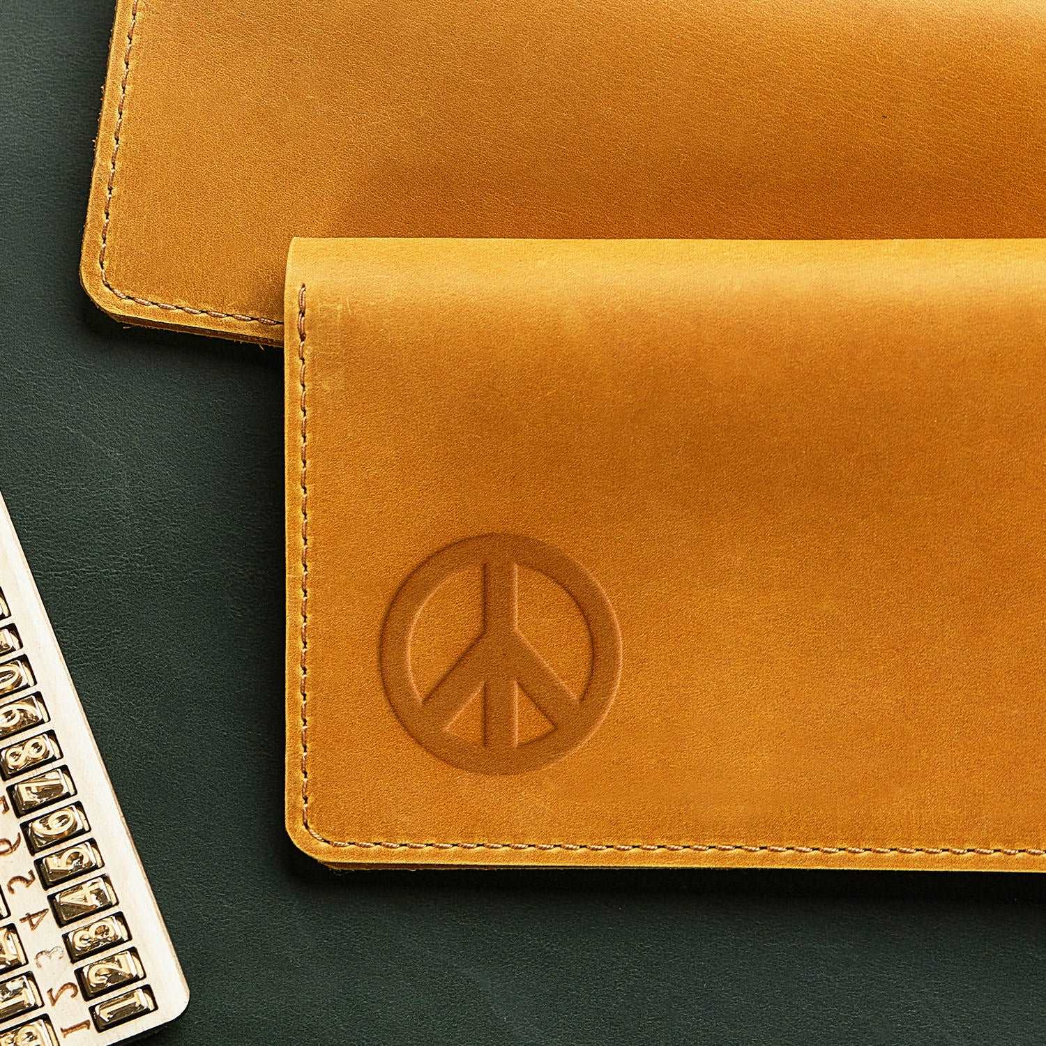 Stamped impression of a classic peace symbol made with a Delrin leather stamp on natural veg-tan leather.