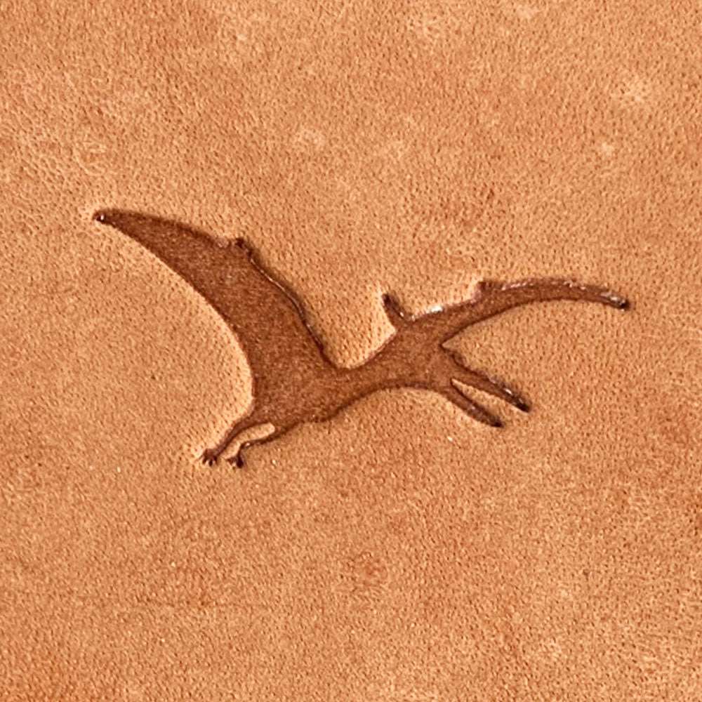 Natural veg-tan leather stamped with a flying pterodactyl silhouette using a Delrin leather stamp, showing clean wing shapes and prehistoric form.
