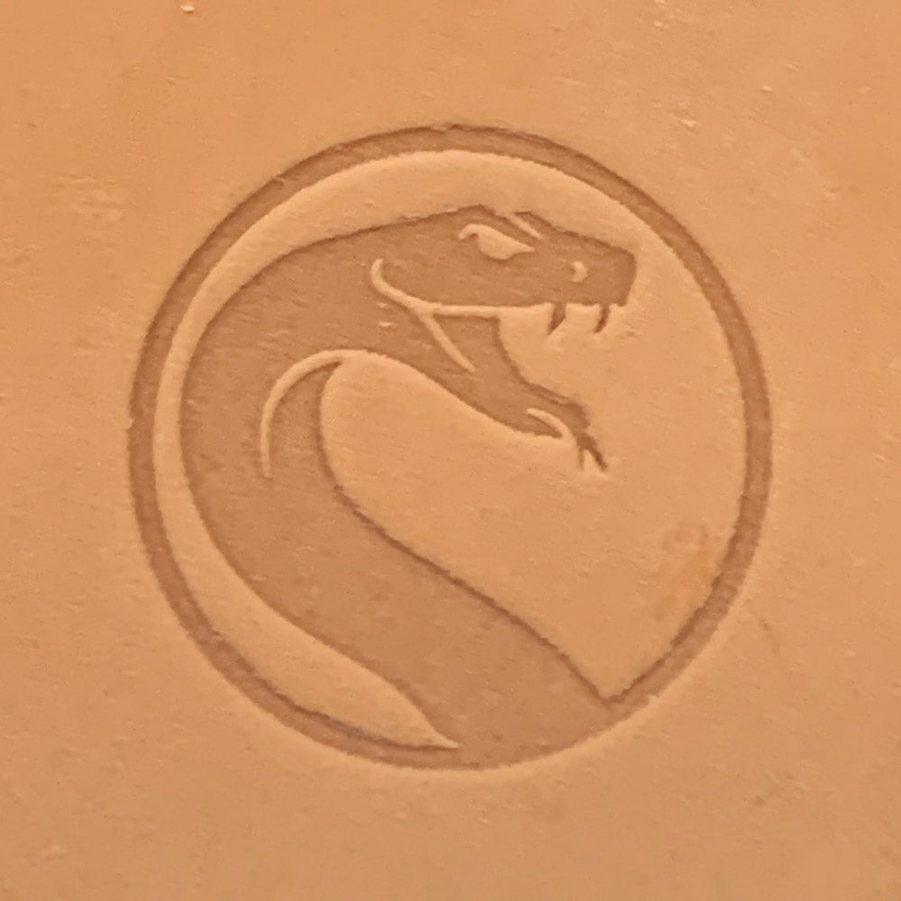 Close-up of vegetable-tanned leather stamped with a circular snake emblem using a Delrin leather stamp.